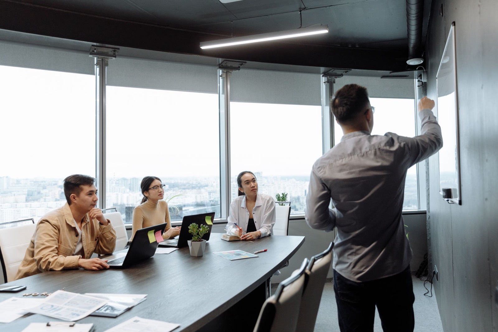 Réunion de travail dans une salle vitrée moderne avec vue sur la ville
